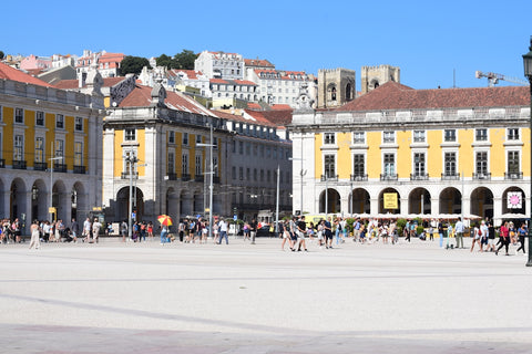 a group of people walking in a plaza with buildings in the background