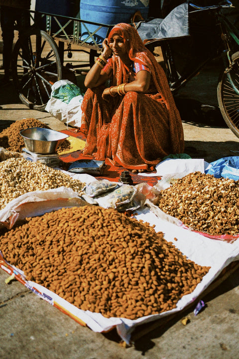a woman sitting on the ground next to a pile of food