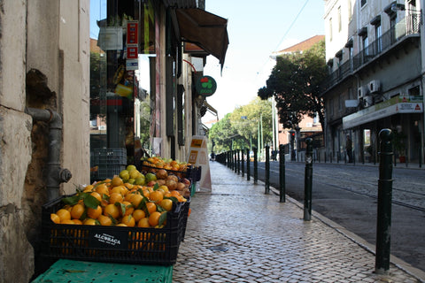 A basket of oranges sitting on the side of a street