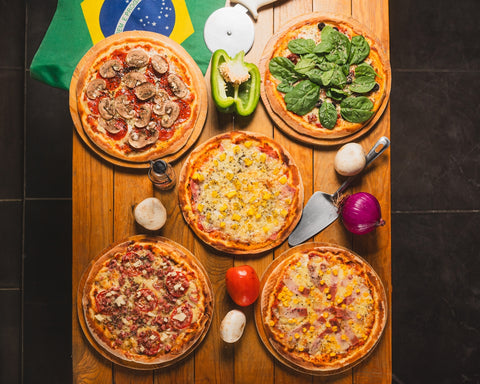 A table topped with four pizzas next to a flag